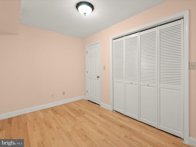 unfurnished bedroom with baseboards, a closet, and light wood finished floors