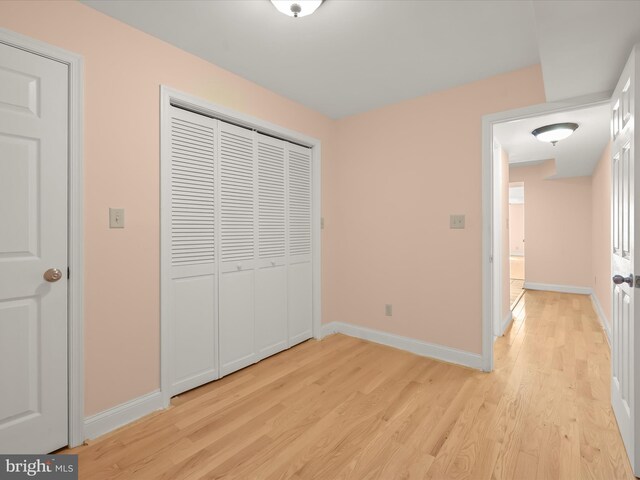 unfurnished bedroom with light wood finished floors, baseboards, and a closet