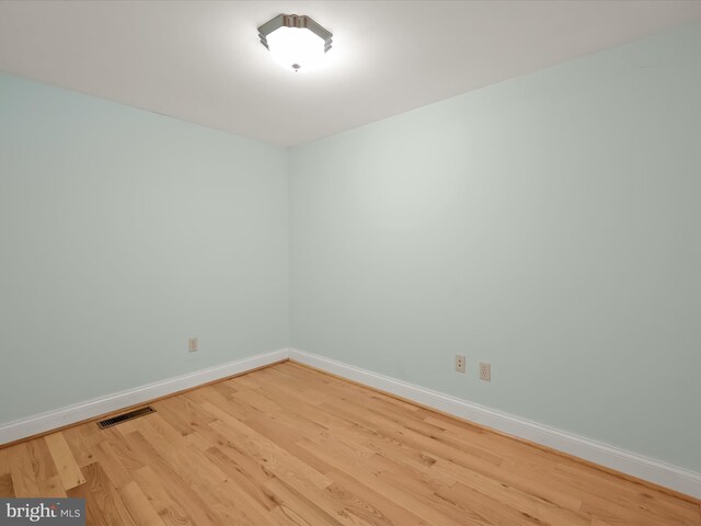 unfurnished room featuring visible vents, baseboards, and wood finished floors