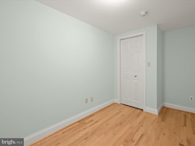 unfurnished bedroom featuring a closet, baseboards, and light wood finished floors
