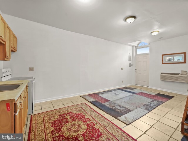 interior space with light tile patterned flooring, baseboards, a wall mounted AC, and light countertops