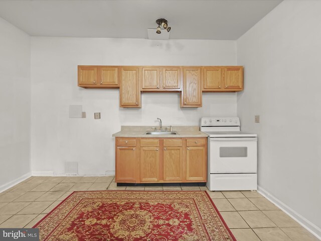 kitchen featuring light countertops, white range with electric stovetop, baseboards, a sink, and light tile patterned flooring