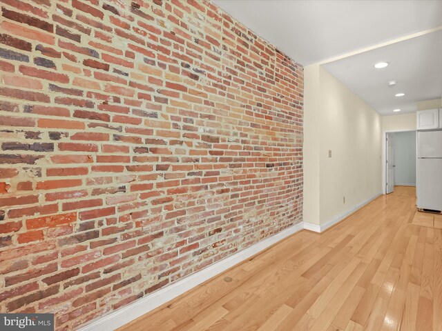 interior space with baseboards, recessed lighting, light wood-type flooring, and brick wall
