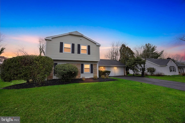 view of front of house featuring a lawn, aphalt driveway, and an attached garage