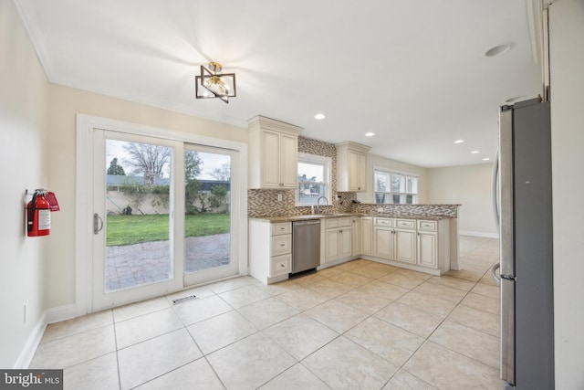 kitchen featuring light tile patterned floors, stainless steel appliances, decorative backsplash, cream cabinets, and a peninsula