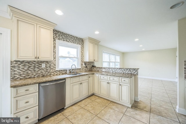 kitchen with a sink, cream cabinets, dishwasher, and a peninsula