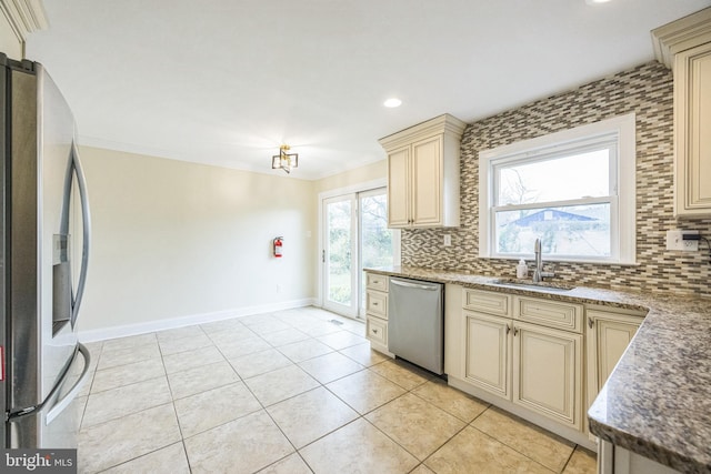 kitchen with cream cabinetry, crown molding, tasteful backsplash, appliances with stainless steel finishes, and a sink