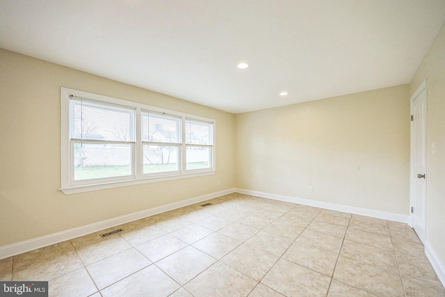 spare room with light tile patterned flooring, baseboards, and visible vents