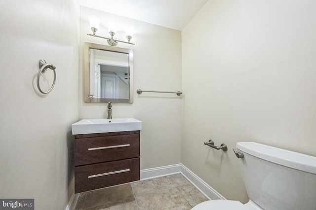bathroom with baseboards, toilet, and vanity