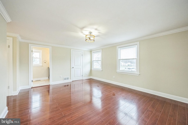 unfurnished room featuring wood finished floors, ornamental molding, and a healthy amount of sunlight