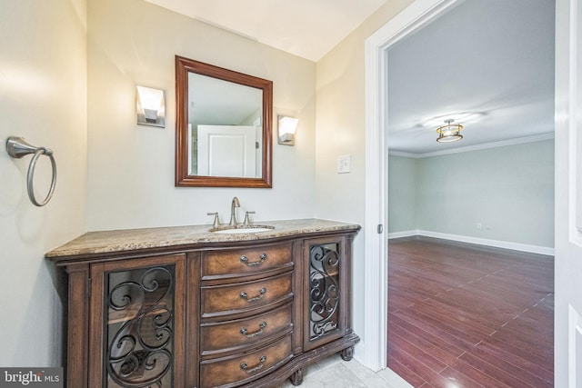 bathroom featuring vanity, crown molding, baseboards, and wood finished floors