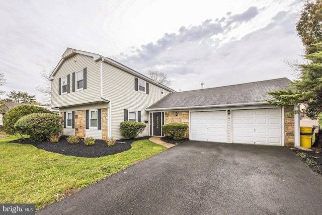 view of front facade with driveway, a front yard, an attached garage, and stone siding
