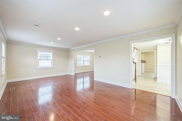 unfurnished room featuring visible vents, crown molding, baseboards, and wood finished floors