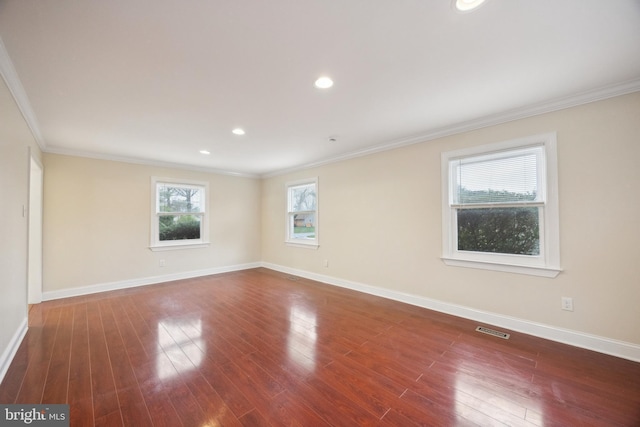 unfurnished room with baseboards, visible vents, crown molding, and wood finished floors