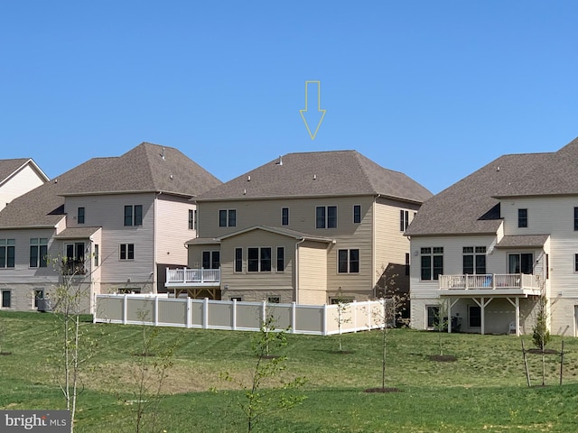 rear view of house featuring a yard and fence