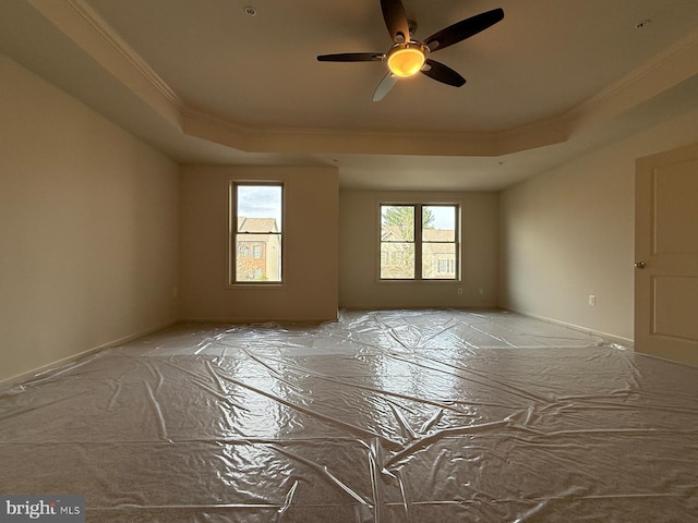 unfurnished room with crown molding, a tray ceiling, ceiling fan, and baseboards