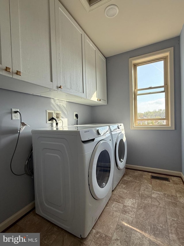 laundry area with cabinet space, visible vents, baseboards, and separate washer and dryer