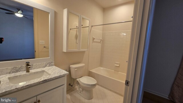 full bath with  shower combination, vanity, a ceiling fan, and toilet