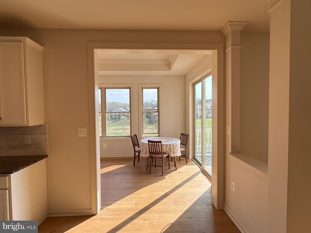 dining space with dark wood-style flooring, baseboards, a raised ceiling, and crown molding