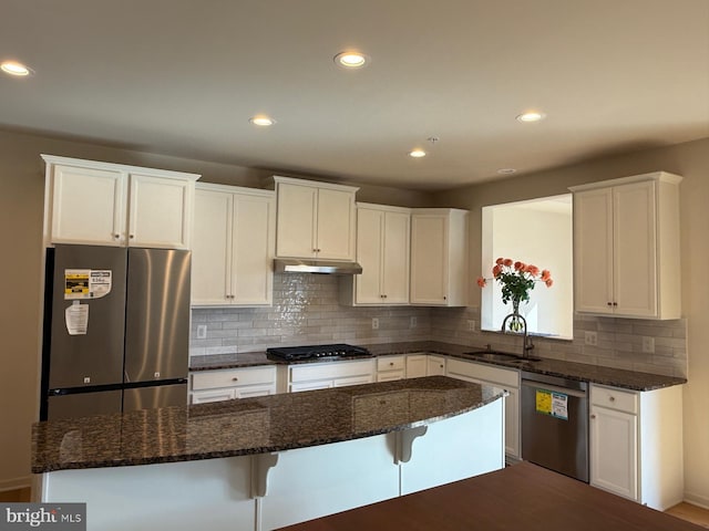 kitchen featuring a sink, a kitchen bar, white cabinetry, stainless steel appliances, and a kitchen island