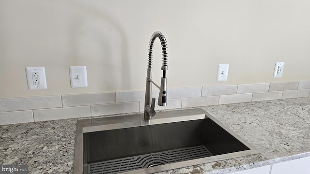 interior details featuring a sink and light stone countertops
