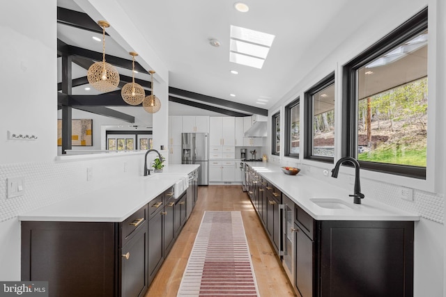 1335 N Pegram St N, Alexandria, VA 22304 - kitchen with vaulted ceiling with skylight, stainless steel refrigerator with ice dispenser, a sink, under cabinet range hood, and white cabinetry