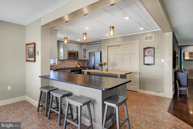 kitchen with baseboards, a kitchen breakfast bar, stainless steel appliances, and visible vents