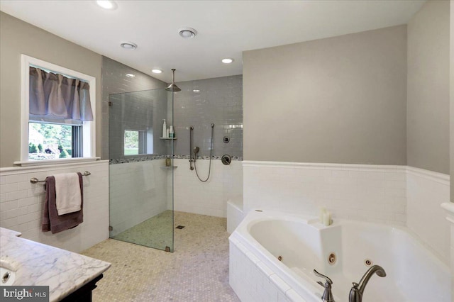 bathroom with vanity, tile walls, walk in shower, a whirlpool tub, and recessed lighting