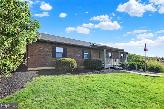 view of front of property with covered porch, brick siding, and a front lawn