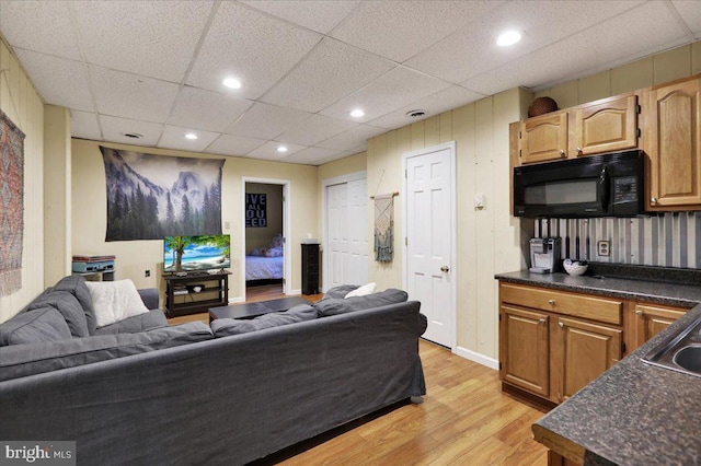living room featuring baseboards, recessed lighting, light wood-style flooring, and a paneled ceiling