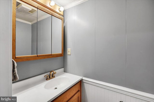 bathroom with vanity, ornamental molding, and a decorative wall