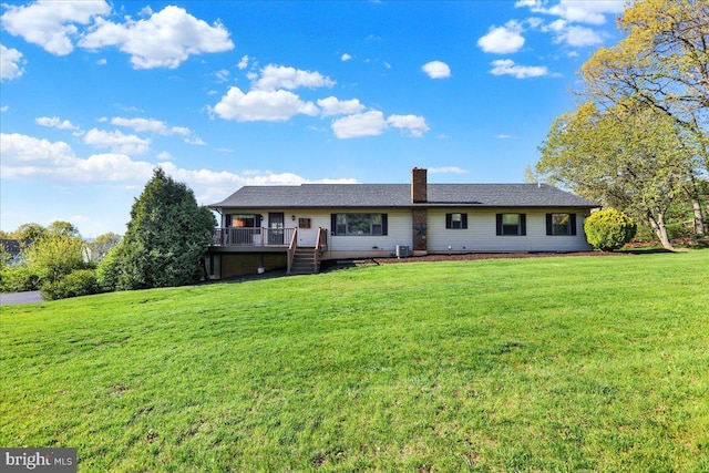 back of house featuring a yard, a wooden deck, and a chimney