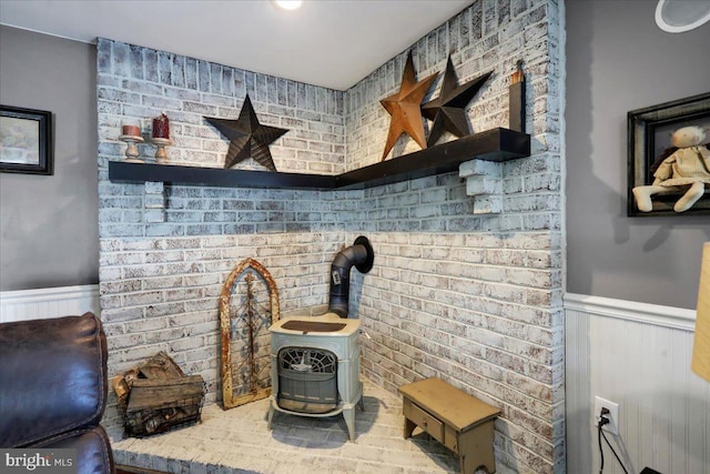 interior details featuring a wood stove and wainscoting