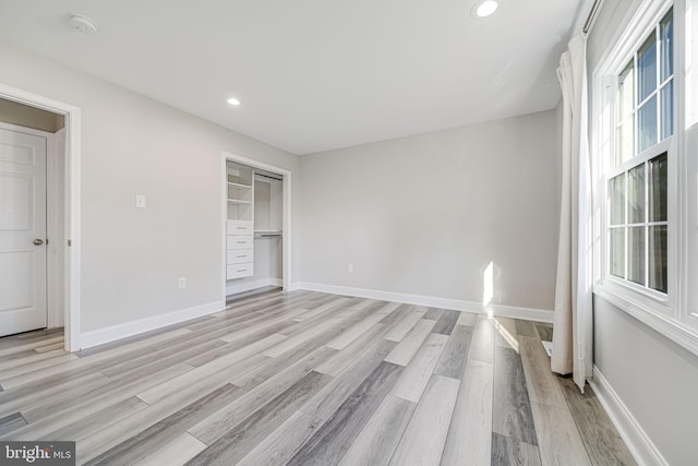 unfurnished bedroom with baseboards, a closet, light wood-style flooring, and recessed lighting