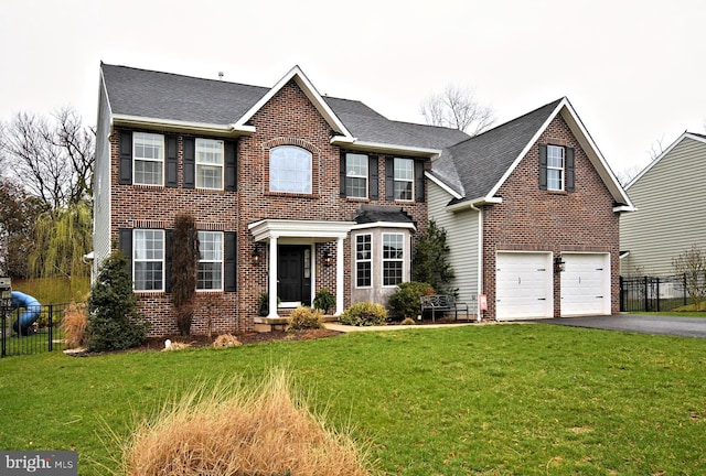 colonial-style house with aphalt driveway, a front yard, fence, and brick siding