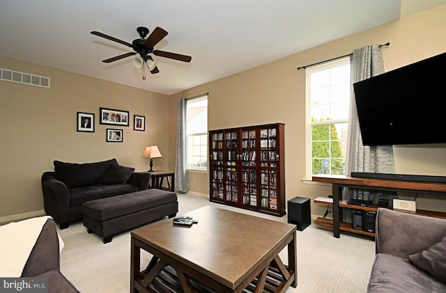 living room featuring visible vents, baseboards, a ceiling fan, and light carpet