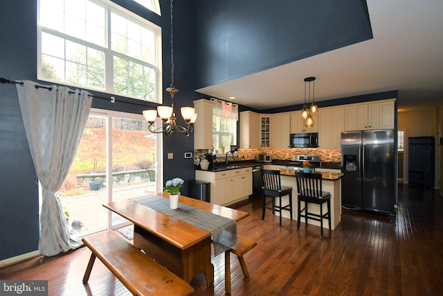 dining space featuring dark wood-type flooring, a high ceiling, and a chandelier