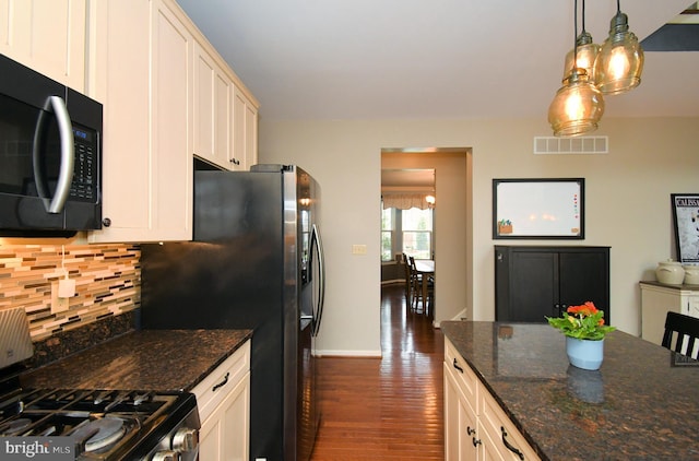 kitchen with visible vents, appliances with stainless steel finishes, dark wood-style floors, dark stone counters, and decorative backsplash