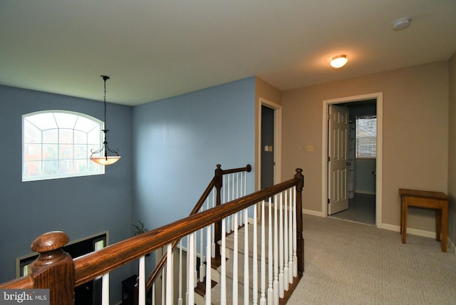 corridor with light carpet, baseboards, and an upstairs landing