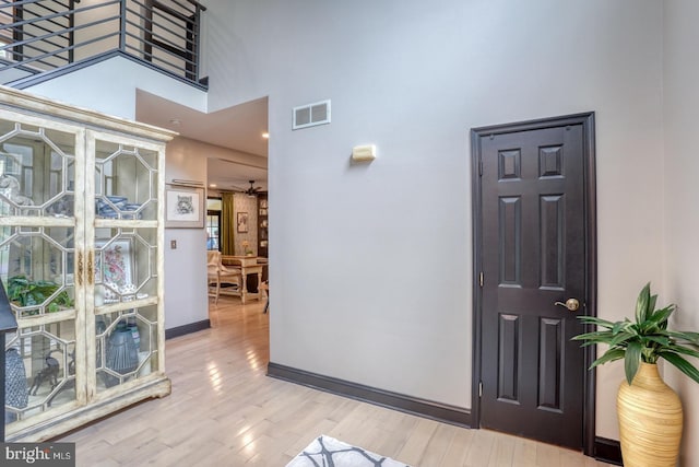 hall featuring a towering ceiling, wood finished floors, and baseboards