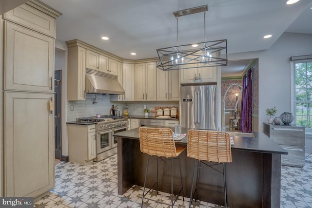 kitchen featuring under cabinet range hood, cream cabinetry, stainless steel appliances, light floors, and recessed lighting