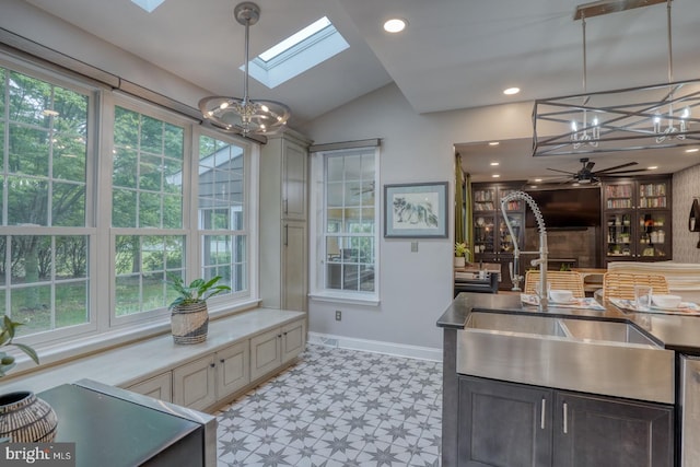 kitchen featuring a chandelier, a sink, light floors, vaulted ceiling, and a skylight