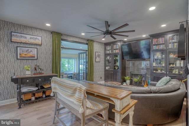 dining area with wallpapered walls, ceiling fan, a tiled fireplace, wood finished floors, and recessed lighting