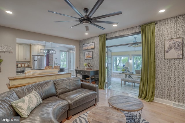 living area with a ceiling fan, wallpapered walls, recessed lighting, light wood finished floors, and baseboards