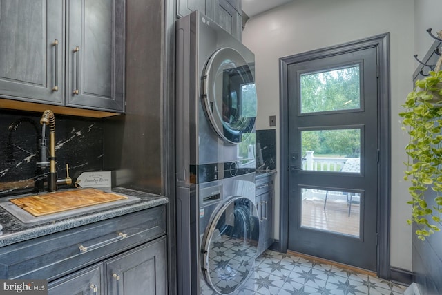 laundry area with stacked washing machine and dryer, light floors, and cabinet space