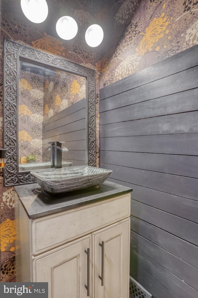 bathroom featuring vanity, wood walls, and wallpapered walls
