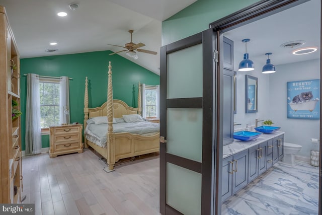 bedroom featuring multiple windows, lofted ceiling, a sink, light wood-style flooring, and recessed lighting