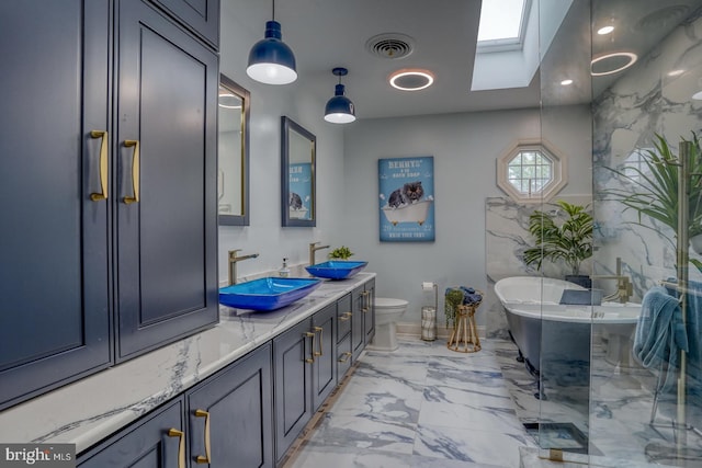 bathroom with a skylight, marble finish flooring, a soaking tub, vanity, and toilet