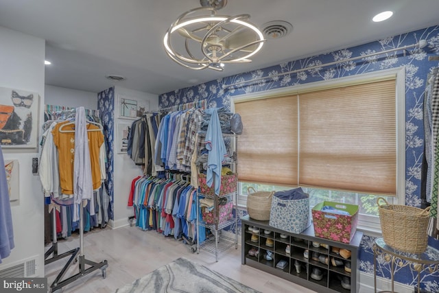 walk in closet with a chandelier and wood finished floors