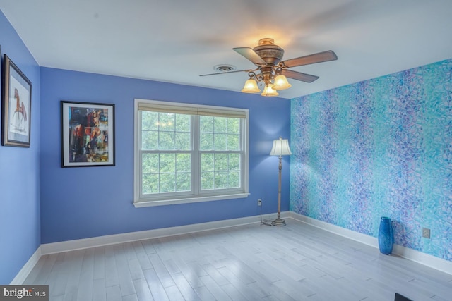 unfurnished room featuring wallpapered walls, wood finished floors, baseboards, and ceiling fan